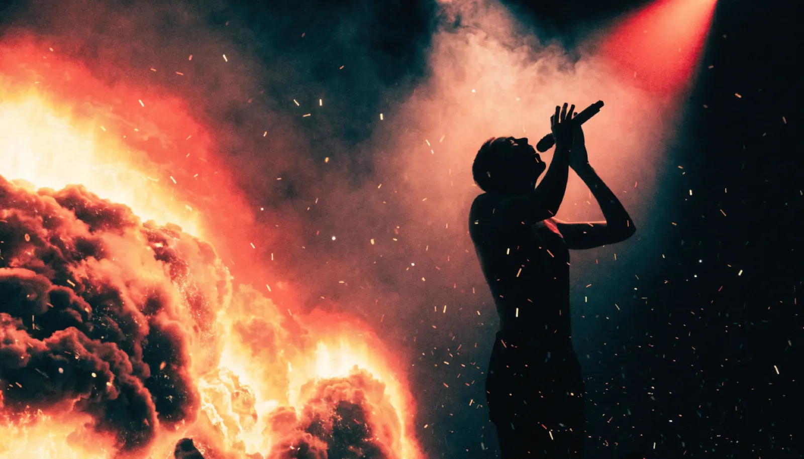 Silueta de cantante ante una proyección de erupción volcánica, videoclip Mestisay Volcán